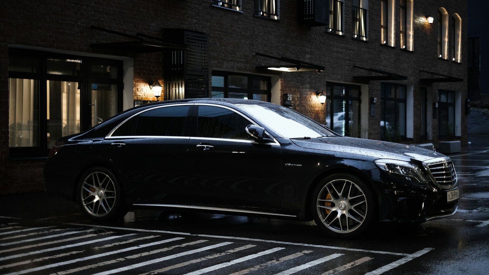 Black luxury sedan parked at night in front of a lit city building